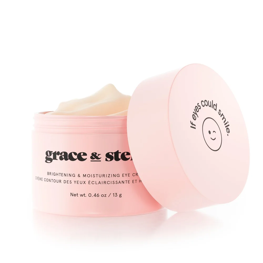 An open pink jar of eye cream with its lid resting against it